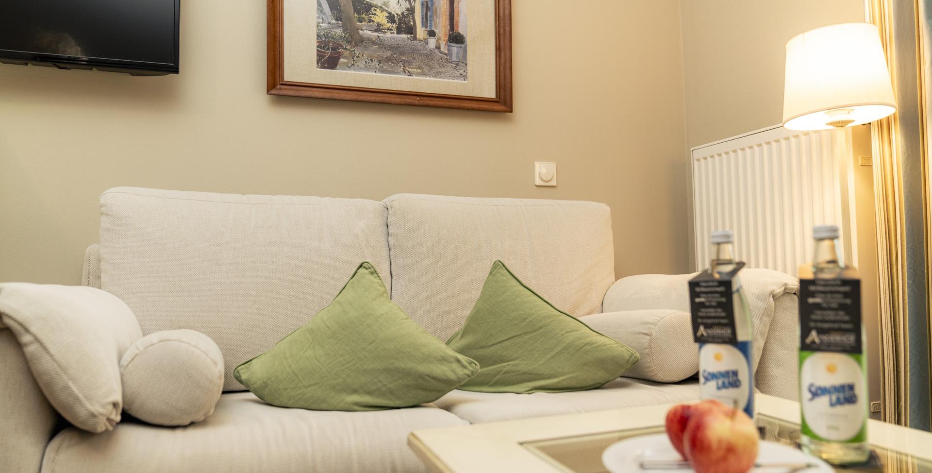 Gemütliche Sitzecke mit hellen Sofas und grünen Kissen im Sport- und Wellnesshotel Angerhof ****S.