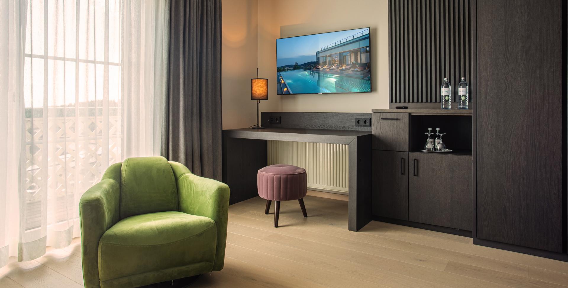 Modernes Zimmer im Sport- und Wellnesshotel Angerhof ****S mit grünem Sessel und TV