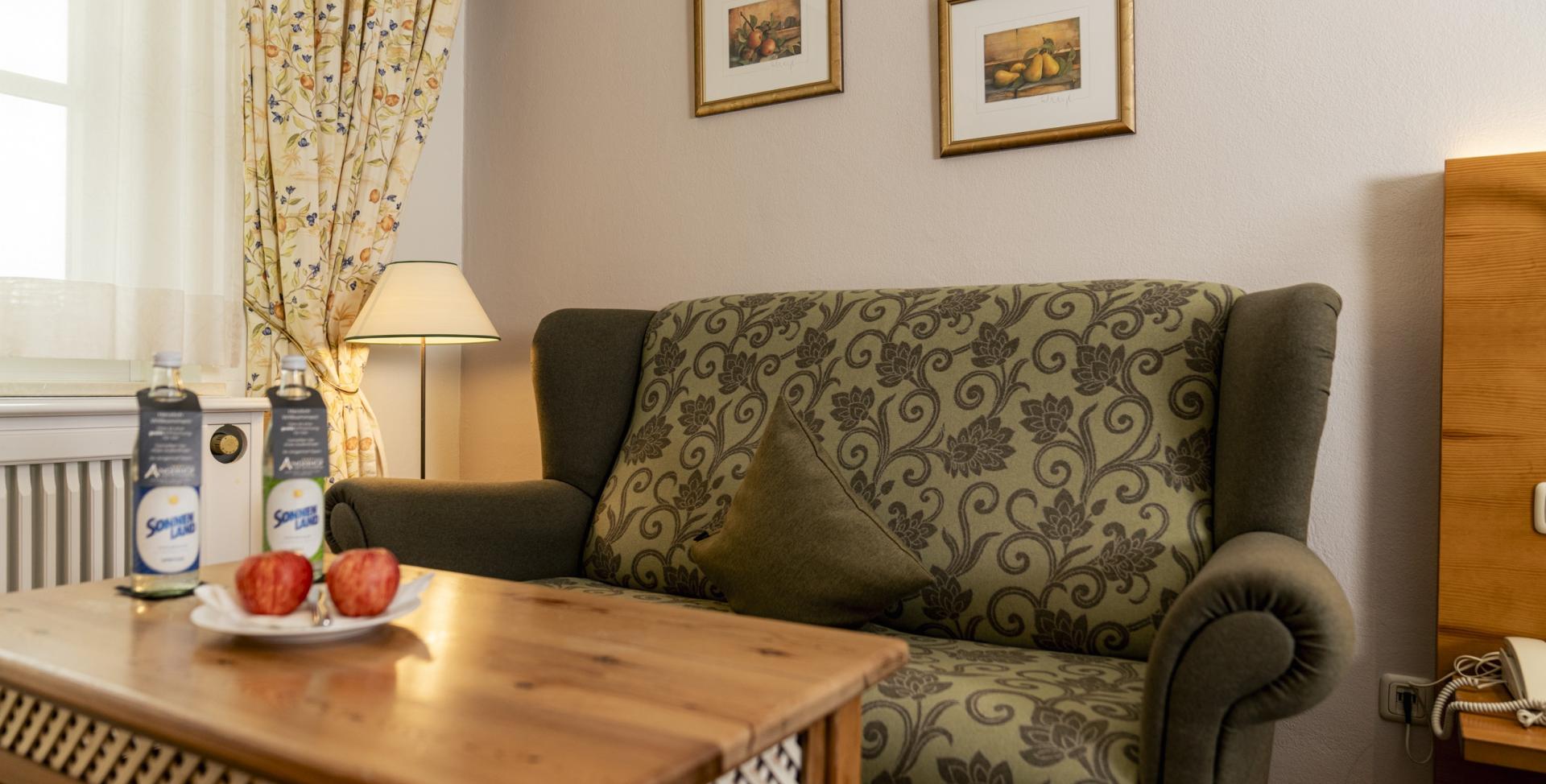 Gemütliche Sitzecke im Sport- und Wellnesshotel Angerhof ****S mit Sofa und Holztisch.
