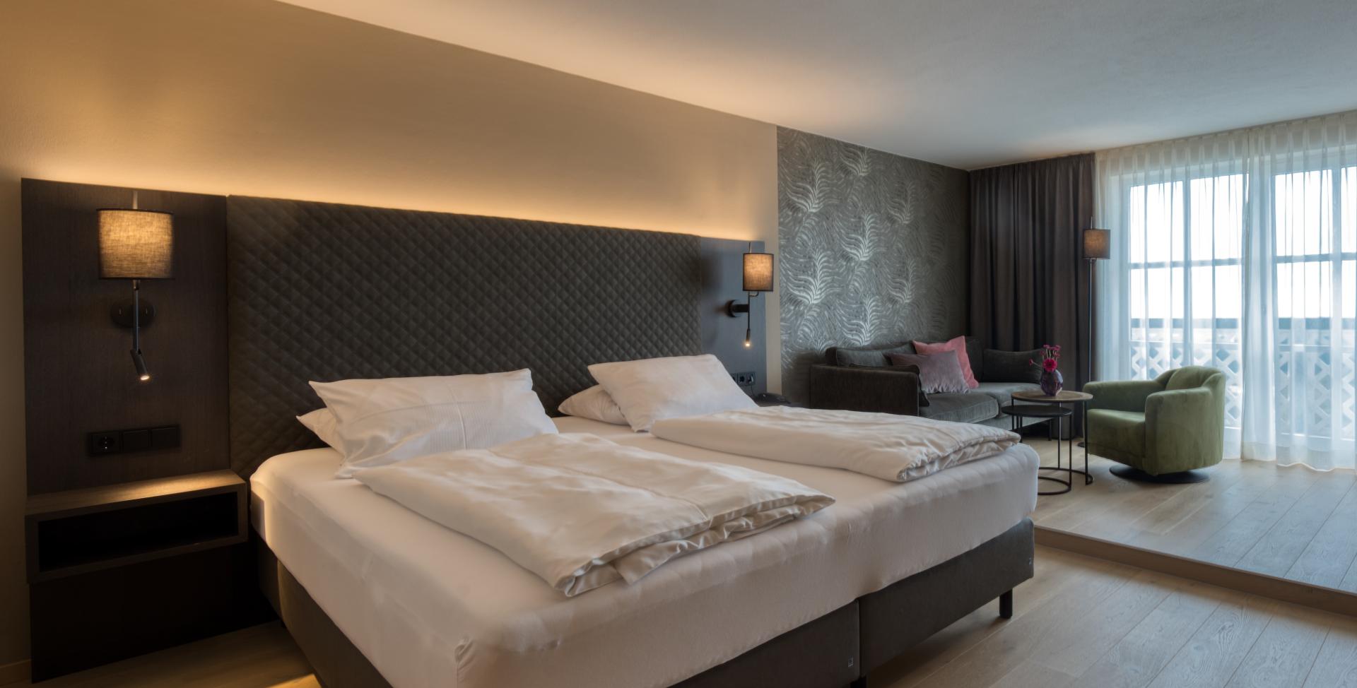 Modernes Schlafzimmer im Sport- und Wellnesshotel Angerhof ****S mit Doppelbett und Sitzbereich