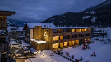 Der Dolomitenhof ***S im winterlichen Abendlicht, umgeben von verschneiten Bergen