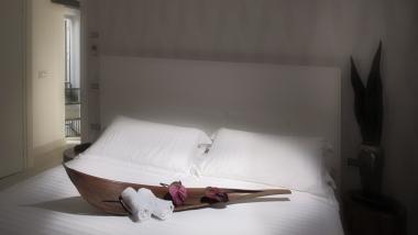 Camera del Q Hotel con letto bianco e vassoio decorativo con asciugamani e fiori