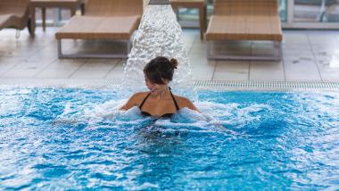 Donna si rilassa nella piscina con massaggio d'acqua da 7th Heaven Beauty & Wellness
