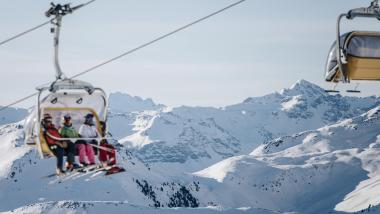 Naturhotel Die Waldruhe Gäste in Sessellift vor verschneiten Bergen