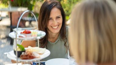 Zwei Frauen beim Essen auf der Terrasse von Castel Sallegg mit mehrstöckiger Platte