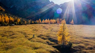Krumers Alpin Wanderer auf herbstlicher Almlandschaft mit Sonne und Bergen