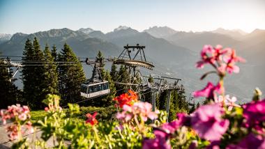Bergbahn und Blumen vor Alpenpanorama beim Sporthotel Silvretta Montafon Gaschurn