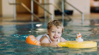 Kleiner Junge schwimmt im Familienresort Buchau mit Spielzeug im Pool