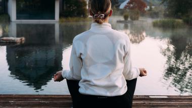 Person meditiert am Wasser im Pfalzblick Wald Spa Resort
