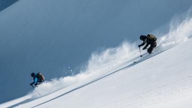 Zwei Skifahrer fahren am Hang mit Schnee bei Hotel Aurora