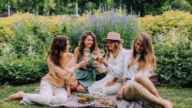 Vier Frauen genießen ein Picknick bei Krumers Alpin im Grünen.