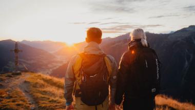 Paar wandert bei Sonnenaufgang Richtung Gipfel in der Region Nationalpark Hohe Tauern