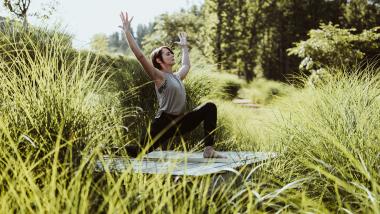 Frau macht Yoga im Freien im Seezeitlodge Hotel & Spa umgeben von grüner Natur