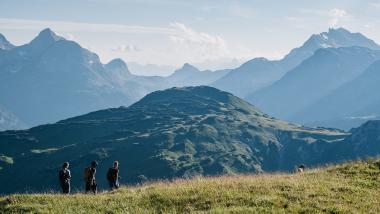 Hotel Aurora Wanderer auf grünem Hügel mit Alpen im Hintergrund