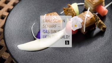 Gourmetgericht auf einem schwarzen Teller kreativ präsentiert.