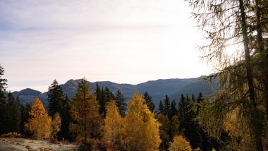 Ziach und Candy stehen auf Gipfeln mit Blick auf Berglandschaft bei Sonnenuntergang