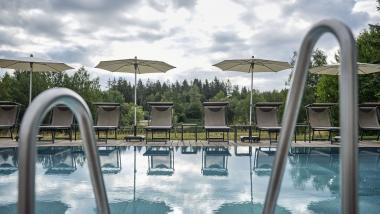 Hotel Reppert Außenpool mit Liegestühlen und Sonnenschirmen bei bewölktem Himmel