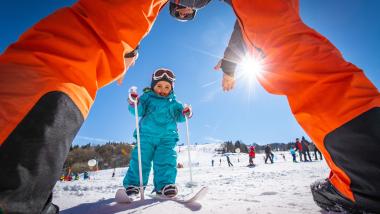 Elgus Nature Retreat: Ein Kind übt Skifahren, eingerahmt von einem Elternteil im Schnee