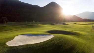 Der Dolomitenhof ***S Golfplatz mit Sandbunker und Bergen im Sonnenuntergang