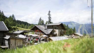 Hotel Adria in the mountains with outdoor seating and guests on a sunny day