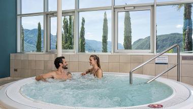 Coppia rilassata in vasca idromassaggio con vista montagna da 7th Heaven Beauty & Wellness