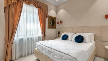 Camera da letto dell'Hotel Regina Caserta con letto matrimoniale e tende eleganti