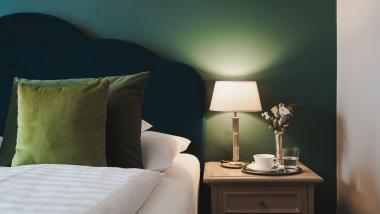 Cozy Hotel Adria room with green headboard and bedside lamp