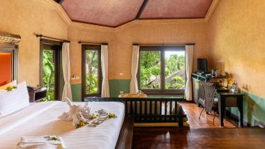 Interior of The Mangosteen Ayurveda & Wellness Resort room with bed and sofa