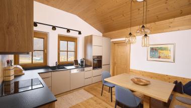 Moderne Küche mit Holzakzenten im Hochfeldhof mit Esstisch und zwei Stühlen