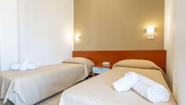 Camera doppia Le Rose Nuove Viserba con copriletti beige e asciugamani bianchi