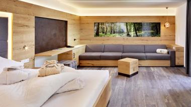 Gemütliches Zimmer im Naturhotel Die Waldruhe mit Holzelementen und großem Sofa.