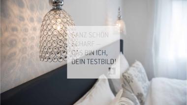 Stilvolles Schlafzimmer mit Pendelleuchten und dekorativen Kissen.