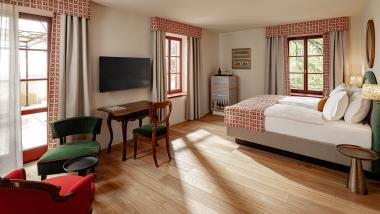 Helles Hotelzimmer mit Doppelbett und Sitzbereich im Castel Sallegg