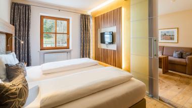Hell eingerichtetes Schlafzimmer im Hammerhof Bodenmais mit Holzboden und Fernseher