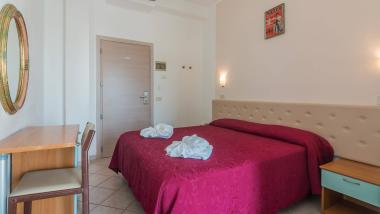 Camera con copriletto rosso e asciugamani piegati a forma di fiori