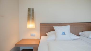 Helles Hotelzimmer mit Bett und Hängelampe im Parkhotel St. Leonhard Überlingen