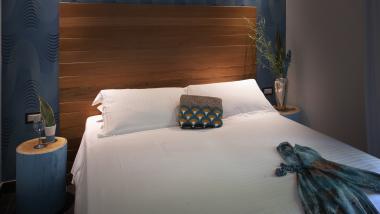 Camera da letto moderna al Q Hotel con letto in legno e accenti blu