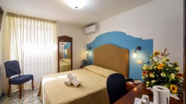 Camera dell'Hotel Amalfi con letto matrimoniale, sfondo blu e fiori