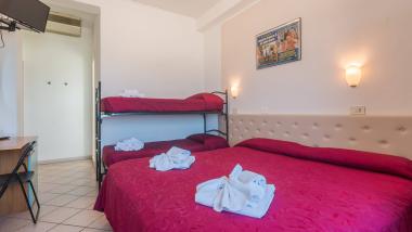 Camera con letti rossi decorati con fiori di asciugamani