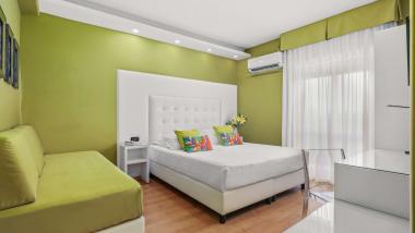 Camera accogliente al Reggia Suite Spa Hotel con divano verde e letto bianco