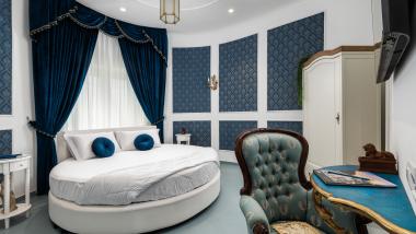 Camera elegante con letto rotondo e tende blu all'Hotel Regina Caserta