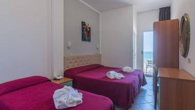 Camera d'hotel con due letti e fiori di asciugamani sulle coperte rosse