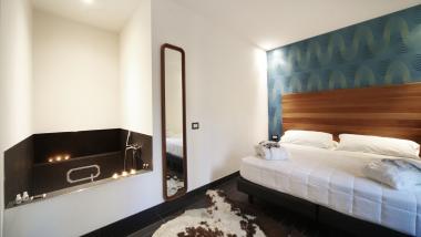 Camera d'albergo moderna al Q Hotel con vasca, specchio e letto comodo