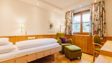 Gemütliches Zimmer im Hotel Aurora mit Holzdekor und einem grünen Sessel