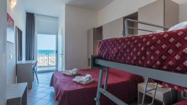 Camera d'hotel con coperte rosse a fiori e vista mare