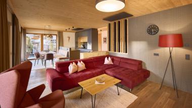 Gemütliches Wohnzimmer mit rotem Sofa und Holzdecke im Hochfeldhof