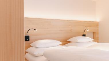 Schlafzimmer mit zwei Betten im Hotel Aurora mit Holzdekor und Leselampen