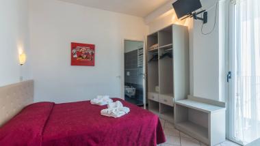 Camera da letto con copriletto rosso a fiori e armadio aperto