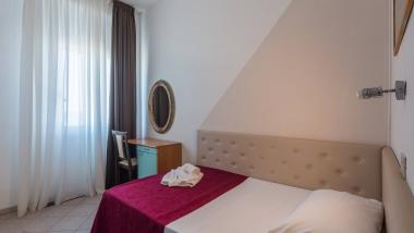 Camera da letto con fiori sul letto e luce naturale dalla finestra