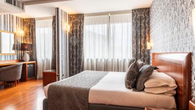 Camera luminosa con letto e carta da parati decorativa al Montresor Hotel Palace Verona